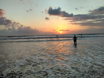 Silhouette man on beach against sky during sunset