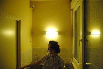 Young woman standing in illuminated bathroom