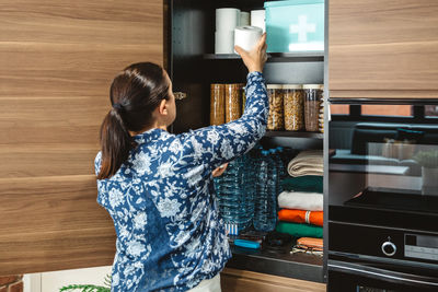 Rear view of woman standing in kitchen