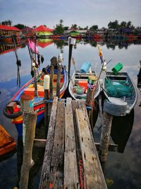 Fishing boats moored in lake against sky