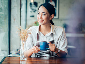 Young woman holding coffee cup on table