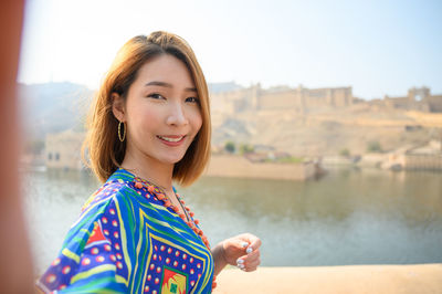 Portrait of smiling young woman against lake