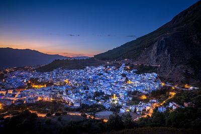 High angle view of illuminated buildings in town against mountains