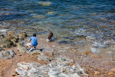 Rear view of man on rock at beach