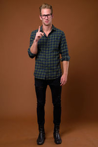 Portrait of young man standing against gray background