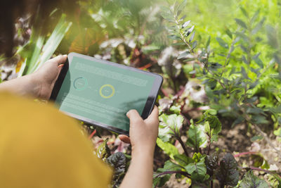 Woman reading plant information on digital tablet in garden