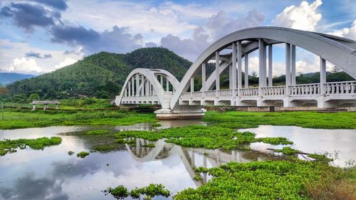 Arch bridge over river against sky