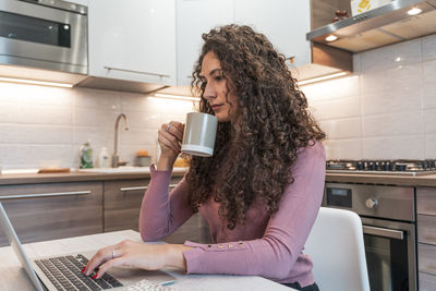 Young woman using mobile phone while sitting at home