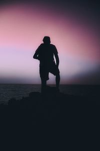 Silhouette man looking at sea against sky during sunset