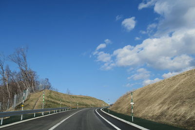 Empty road along landscape against blue sky