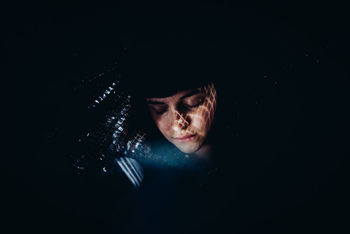 PORTRAIT OF WOMAN AGAINST DARK BACKGROUND