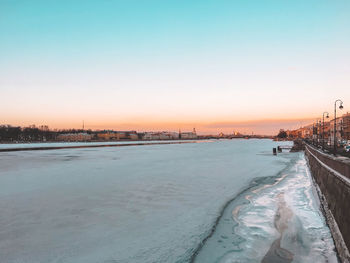 Scenic view of frozen river against sky during sunset