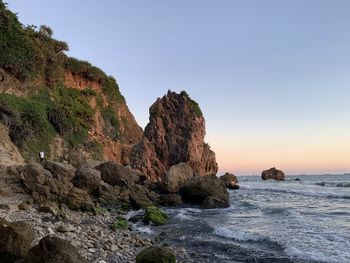 Rocks on sea shore against clear sky