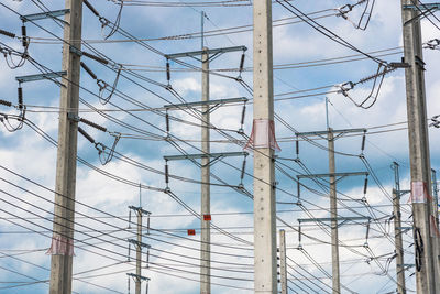 Electricity pylon against sky seen through fence