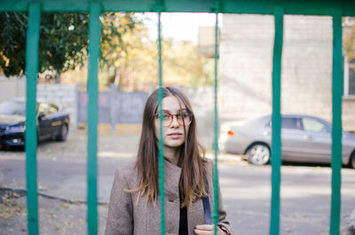 Portrait of young woman looking through gate