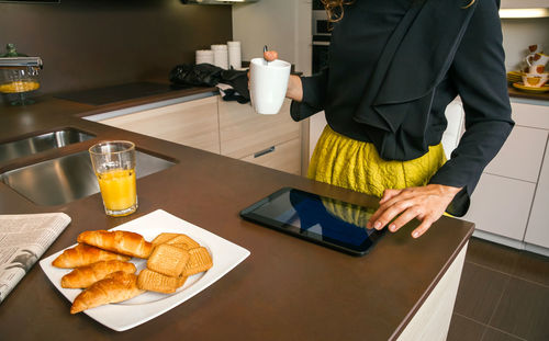 Midsection of woman having food at home