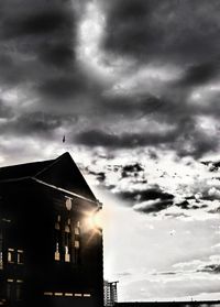 Low angle view of silhouette building against cloudy sky