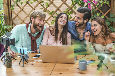 Cheerful friends using laptop at table