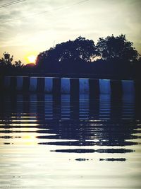 Reflection of silhouette trees on lake against sky during sunset