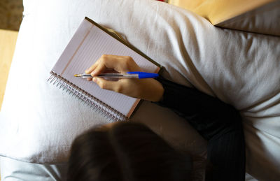 Woman lying in bed writing on her datebook.