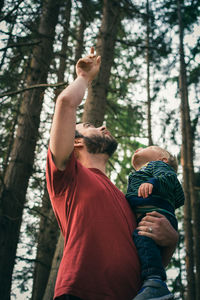 Midsection of woman with arms raised in forest