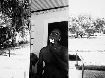 Portrait of shirtless man standing against trees