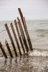 Wooden posts on beach against sky