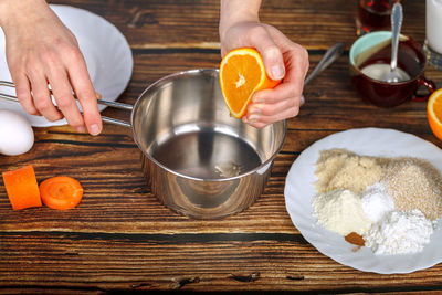 Hand squeezes orange juice into a metal bowl