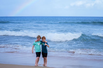 Young boys playing in the waves with a rainbow over the ocean on ka'anapali beach in hawaii. 