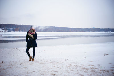 Full length of woman standing on beach against clear sky