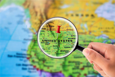 Close-up of person hand holding magnifying glass over map