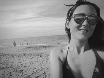 Portrait of young woman on beach against sky