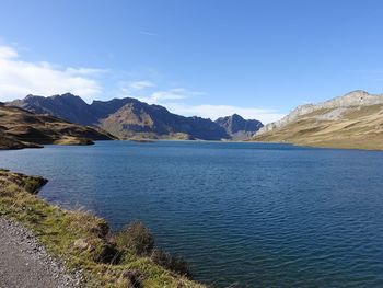 Scenic view of lake and mountains against blue sky