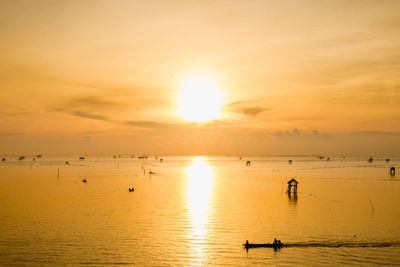 Fishing boat for small fish in the sea with sunset background, silhouette concept.