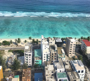 High angle view of buildings by sea against blue sky