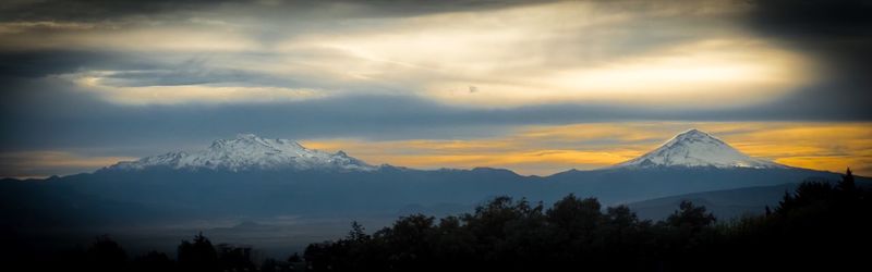 Panoramic shot of snow covered mountains against sky during sunset