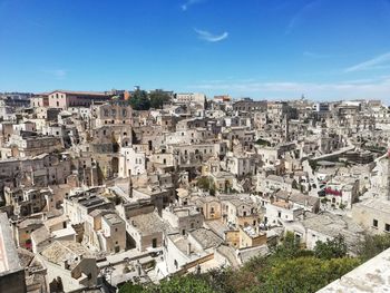 High angle view of buildings in city against blue sky