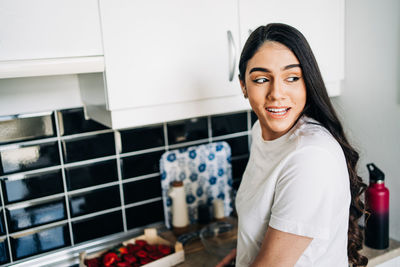 Portrait of a smiling young woman in kitchen at home