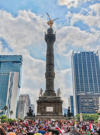 Group of people in front of building against cloudy sky