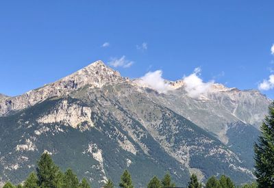 Low angle view of snowcapped mountains against blue sky