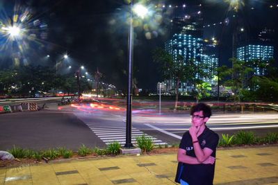 Woman standing on city street at night