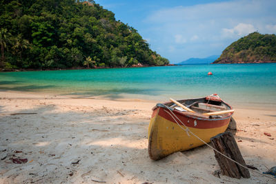 Boat moored on beach against sky