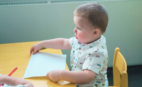 Cute boy holding paper at table