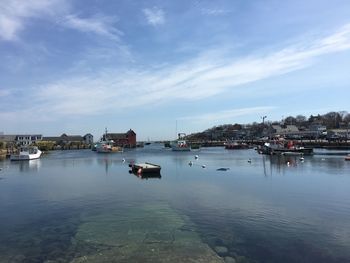 Sailboats in harbor by buildings against sky