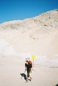 People on sand dune against clear sky