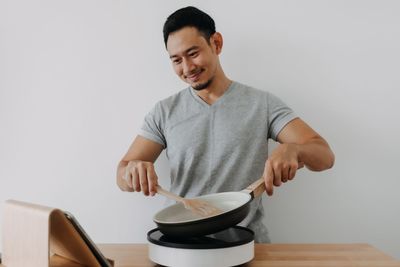 Portrait of senior man cutting vegetables on table against white background