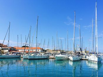 Sailboats moored in harbor against clear blue sky
