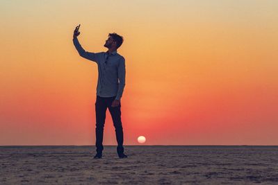 Full length of man standing on beach during sunset