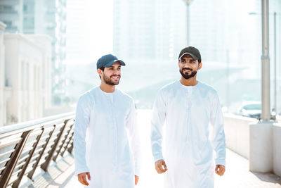 Men walking on footpath against building