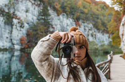 Portrait of young woman taking photos of beautiful autumn nature with a vintage film camera